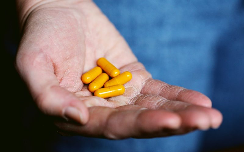 yellow medication pill on persons hand
