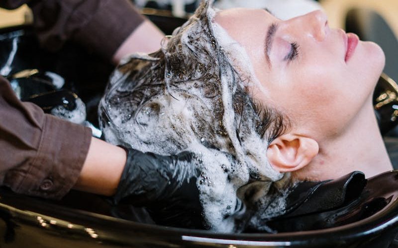 Professional hair stylist washing woman's hair in a modern salon setting.