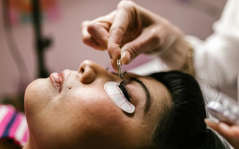 Close-up of a woman receiving eyelash extensions at a beauty salon.